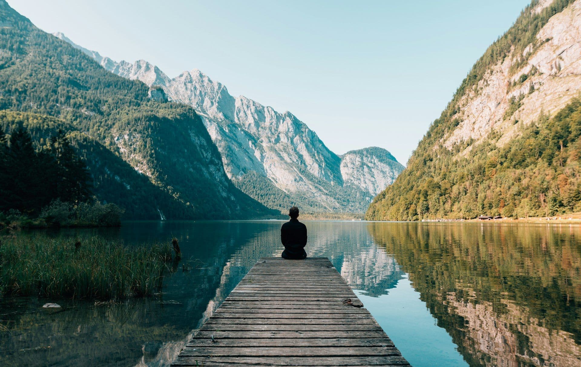 Meditating at the end of a pier on a calm mountain lake