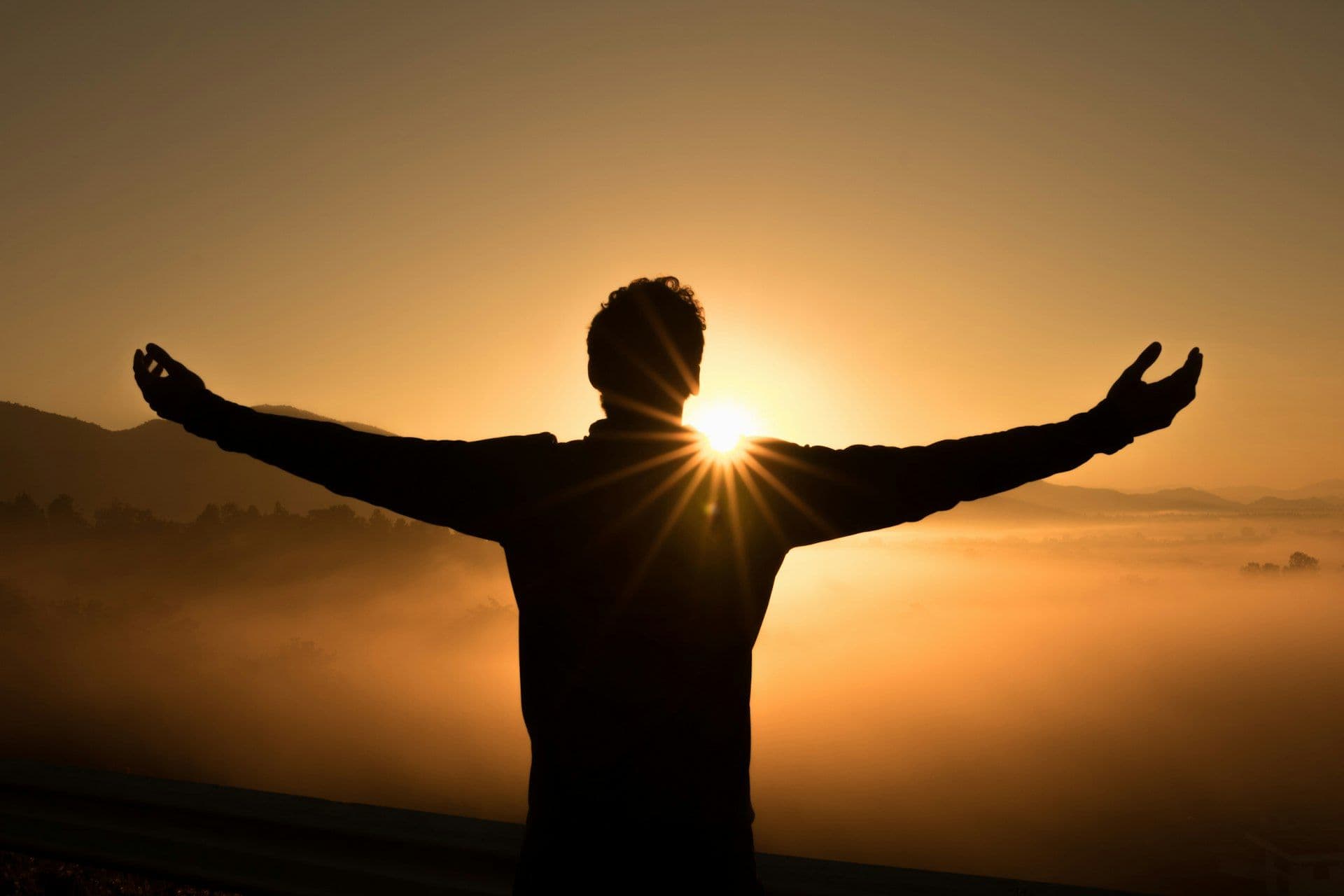 Person with open arms welcoming the sunrise